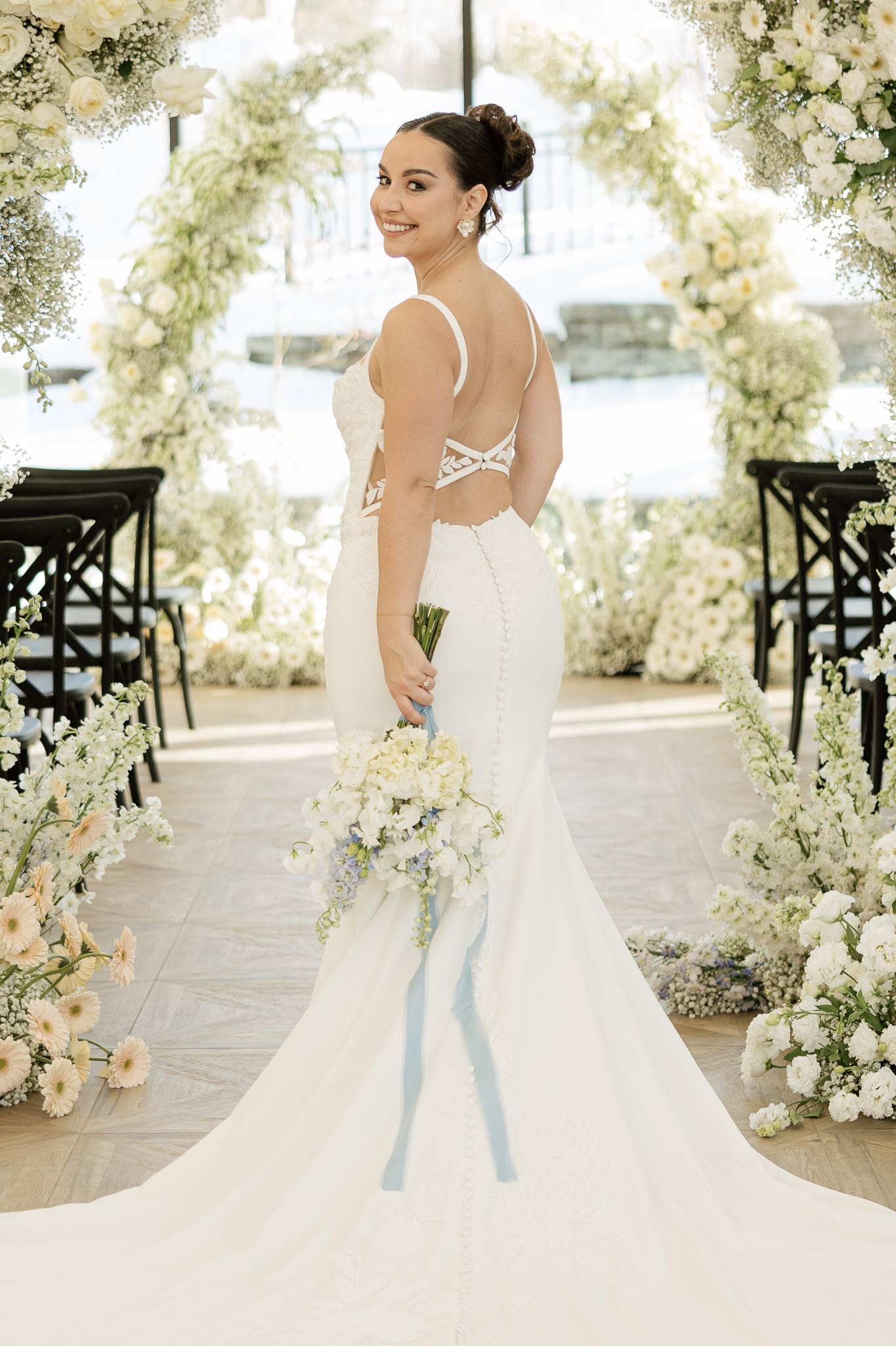 Bridal portrait at Crossed Keys Estate in New Jersey. Bride looking back to photographer with wedding flowers and long train.