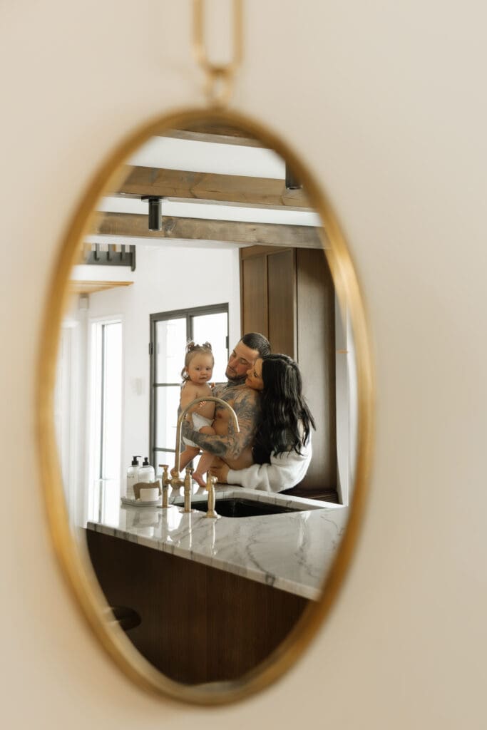 Expecting mother embracing husband and daughter in a natural motherhood portrait.